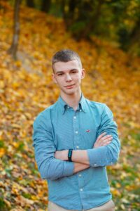 man in blue dress shirt standing near brown leaves during daytime